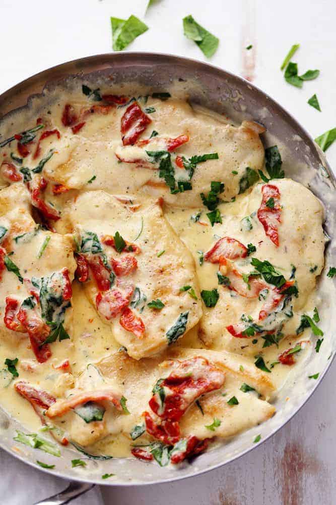 Creamy Tuscan Garlic Chicken has the most amazing creamy garlic sauce with spinach and sun dried tomatoes. This is a restaurant quality meal that's easy to make at home in just 30 minutes! Creamy Tuscan Garlic Chicken in a large pan.