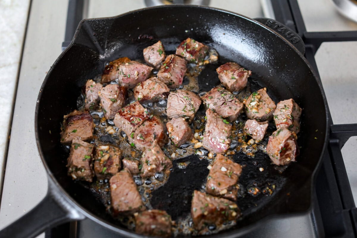 Seared steak pieces with garlic and herbs added. 