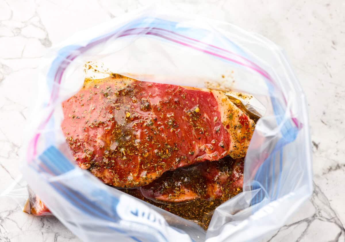 Overhead shot of steak covered in marinade in a zip lock bag. 